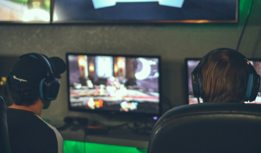 Dos chicos de espaldas con auriculares jugando a un videojuego