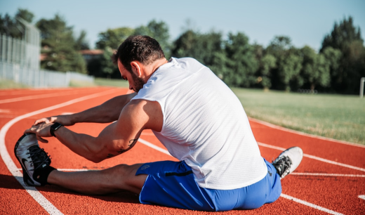 Chico en pista de atletismo realizando estiramientos