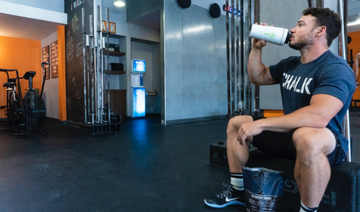 Chico sentado en un gimnasio bebiendo de un termo