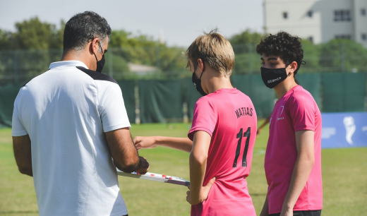 Chicos con su entrenados mirando una tabla de entrenamiento