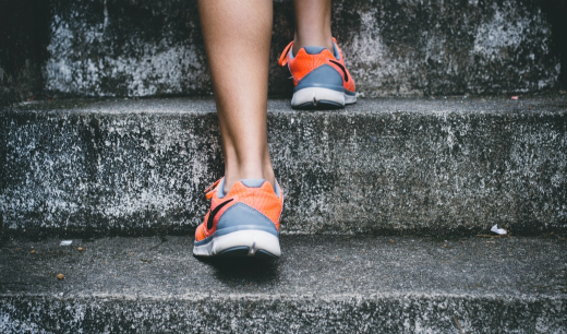Piernas con zapatillas subiendo escaleras de piedra