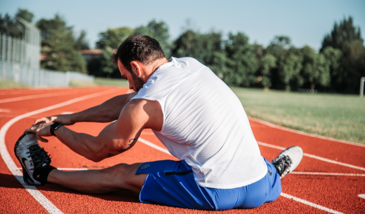Chico en pista de atletismo realizando estiramientos