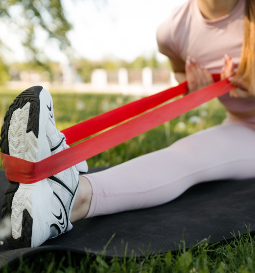 Chica estirando el pie con una goma elástica en el parque