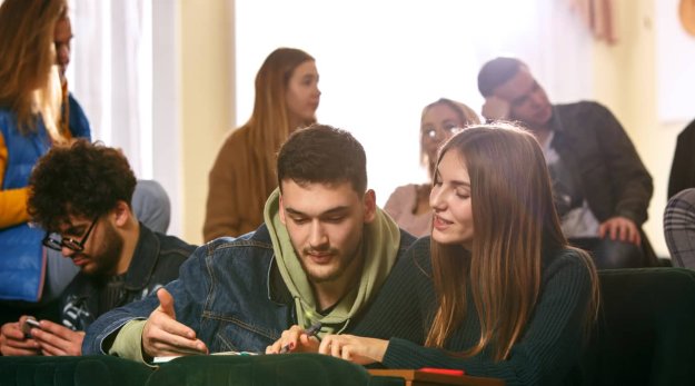 Un grupo de estudiantes sentados en una sala de conferencia e intercambiando palabras