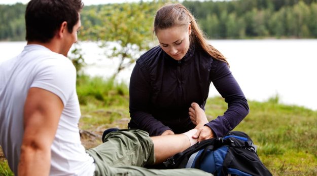 Mujer practicando los primeros auxilios en un accidente en el medio natural