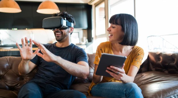 Una pareja experimentando con la realidad virtual mientras están en el sofá