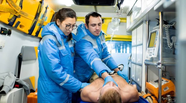 Dos técnicos sanitarios ofreciendo asistencia a un paciente dentro de una ambulancia