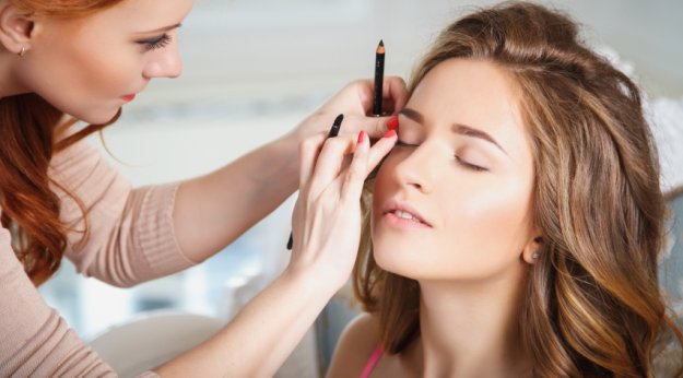 Maquilladora difuminando la línea del ojo de una clienta