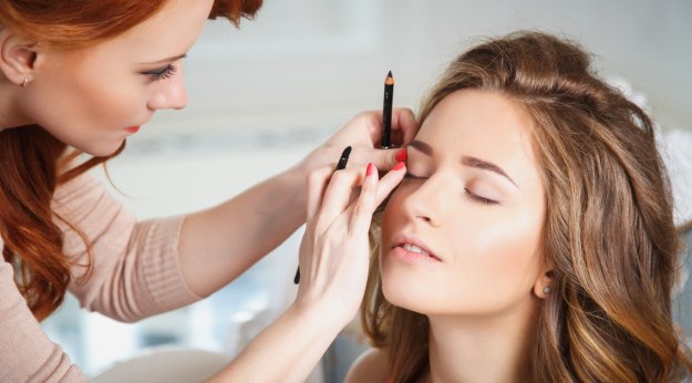Maquilladora difuminando la línea del ojo de una clienta