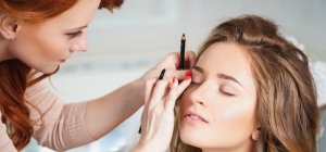 Maquilladora difuminando la línea del ojo de una clienta